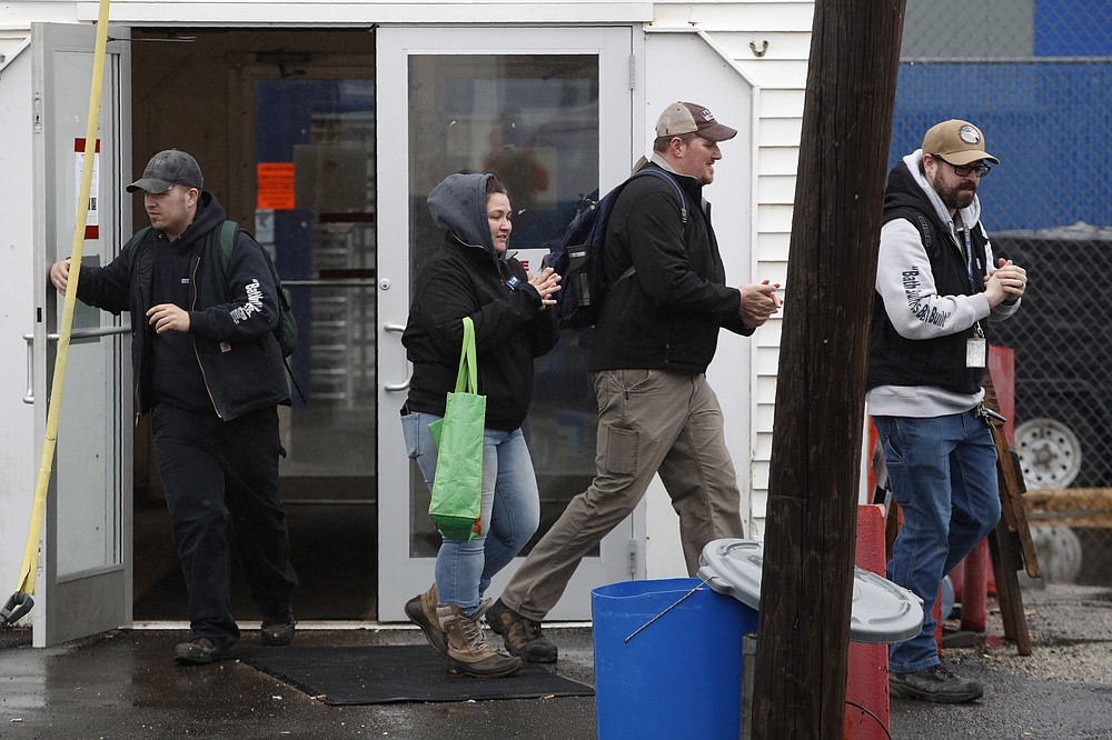 FILE - In this April 3, 2020, file photo, workers rub their hands with hand sanitizer as they leave Bath Iron Works in Bath, Maine. Workers at one of the Navy’s largest shipbuilders overwhelmingly voted to strike, rejecting Bath Iron Works’ three-year contract offer Sunday, June 21 and threatening to further delay delivery of ships. (AP Photo/Robert F. Bukaty, File)