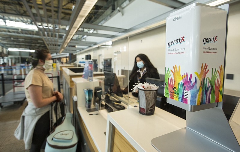 Gwena Dye (left), a student at John Brown University returning home to Italy, checks in for her flight Wednesday, May 13, 2020, with Sandra Valle at the Delta Airlines desk at Northwest Arkansas National Airport in Highfill. The airport has installed sneeze guards at desks where staff interact with passengers and hand sanitizer dispensers throughout the airport. Go to nwaonline.com/200517Daily/ to see more photos.
(NWA Democrat-Gazette/Ben Goff)