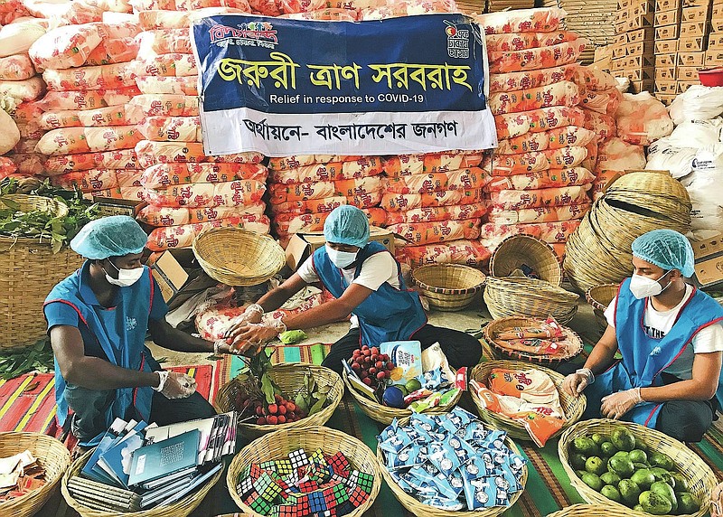 Members of Bidyanondo Foundation pack care packages for COVID-19 patients in Dhaka, Bangladesh, Saturday, June 6, 2020. The Bangladeshi group of volunteers is providing COVID-19 patients with fruit baskets and “get well soon” cards to keep their spirits up amid reports that many patients are being ostracized by their families and neighbors. The group stepped in after disturbing news reports that a woman has been abandoned in a forest by her family after she developed coronavirus symptoms. (AP Photo/Al-emrun Garjon)