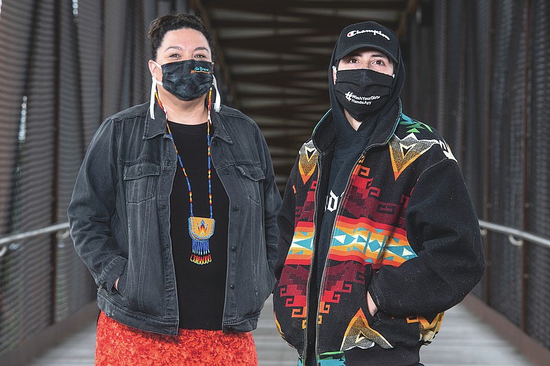 In this photo taken June 16, 2020, Artie Mendoza III and Michelle Mitchell, left, stand for a portrait on the pedestrian bridge overlapping Highway 93 in Pablo, Montana. Mendoza, also known as KiidTruth, is a well known hip-hop artist on the Flathead Indian Reservation. The duo have been using the social media platform TIk Tok to promote hand washing and mask wearing among the youth to prevent the spread of COVID-19 on the reservation. "Our guiding work is for the youth here on the reservation, but that doesn't mean our kids over here can't challenge the kids from Blackfeet," Mitchell said. "They could launch these challenges themselves and take it in to other Indian communities. That would be pretty cool." (AP Photo/Tommy Martino)