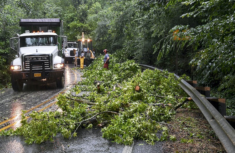 A Mack truck, left, drives past a crew of Hot Springs National Park workers removing a tree from the roadway after it fell on Gulpha Gorge Road during a storm in the area on Tuesday. - Photo by Grace Brown of The Sentinel-Record