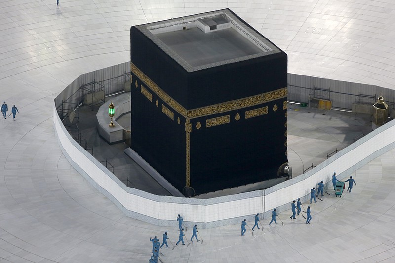 FILE - In this March 7, 2020 file photo, workers disinfect the ground around the Kaaba, the cubic building at the Grand Mosque, in the Muslim holy city of Mecca, Saudi Arabia after authorities emptied Islam's holiest site for sterilization over fears of the new coronavirus. This was supposed to be Saudi Arabia's year to shine as host of the prestigious G20 gathering of world leaders. Instead, due to the pandemic, the gathering this November will likely be a virtual meet-up, stripping its host of the pomp that would have accompanied televised arrivals on Riyadh's tarmac. Even the upcoming hajj pilgrimage faces the possibility of being canceled or dramatically pared down. (AP Photo/Amr Nabil, File) story.lead_photo.caption