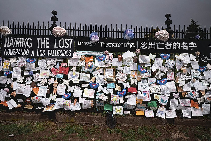 FILE - In this Thursday, May 28, 2020 file photo, a fence outside Brooklyn's Green-Wood Cemetery is adorned with tributes to victims of COVID-19 in New York. The memorial is part of the Naming the Lost project which attempts to humanize the victims who are often just listed as statistics. The wall features banners that say "Naming the Lost" in six languages — English, Spanish, Mandarin, Arabic, Hebrew, and Bengali. Some worry a large new wave of coronavirus might occur in the fall or winter of 2020 — after schools reopen, the weather turns colder and less humid, and people huddle inside more. (AP Photo/Mark Lennihan)