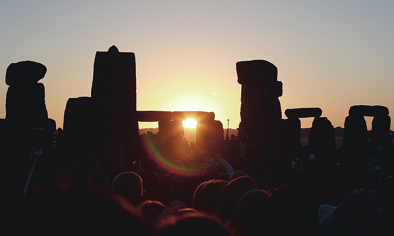FILE - In this June 21, 2019, file photo, the sun rises as thousands of revelers gather at the ancient stone circle Stonehenge to celebrate the Summer Solstice, the longest day of the year, near Salisbury, England. The coronavirus pandemic has scuttled summer solstice celebrations at Stonehenge, a highlight of the year for thousands of British pagans, druids and assorted revelers. English Heritage, which looks after the ancient stone circle, says restrictions on public events to slow the spread of the virus make it impossible to hold the event. It said it had decided to cancel the gathering “after much deliberation and in consultation with our partners in the police and the emergency services, the druid and pagan community and others.” (AP Photo/Aijaz Rahi, File)