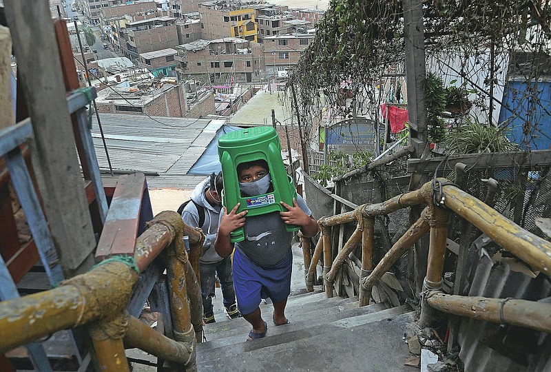 Twelve-year-old Yacdel Flores, hauling hard plastic stools, ascends a flight of stairs to the top of a hill to receive a free haircut from 21-year-old barber Josue Yacahuanca, in the San Juan de Lurigancho neighborhood of Lima, Peru, Friday, June 19, 2020. There are around 150,000 hairdressers in Peru, but Yacahuanca is one of the few who decided to offer his services for free to those most in need amid the new coronavirus pandemic. (AP Photo/Martin Mejia)