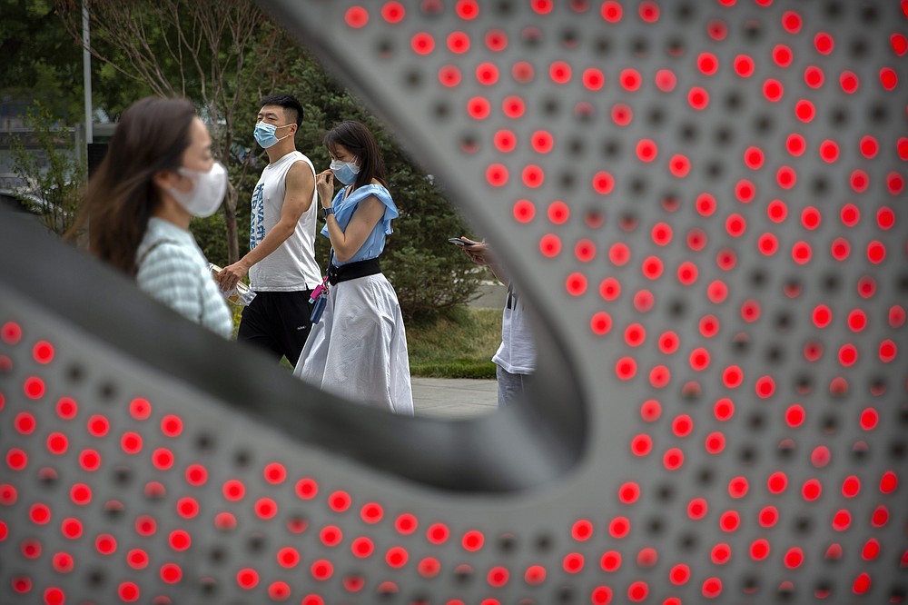 People wearing face masks to protect against the spread of the new coronavirus walk through a shopping and office complex in Beijing, Wednesday, June 24, 2020. New virus cases have declined in China and in the capital Beijing, where a two-week spike appears to be firmly waning. (AP Photo/Mark Schiefelbein)