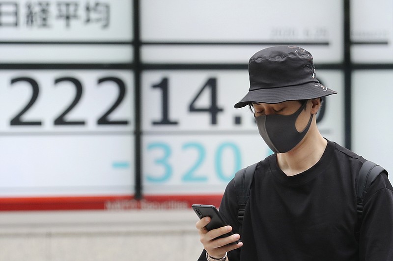 A man walks by an electronic stock board of a securities firm in Tokyo, Thursday, June 25, 2020. Shares declined in Asia on Thursday after a sharp retreat overnight on Wall Street as new coronavirus cases in the U.S. climbed to their highest level in two months, dimming investors' hopes for a relatively quick economic turnaround. (AP Photo/Koji Sasahara)