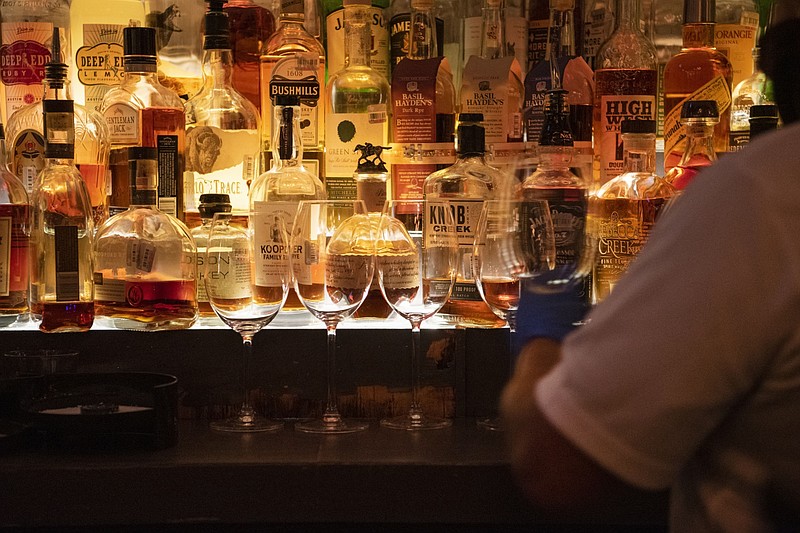 A bartender wearing gloves cleans glasses at a restaurant in Houston on May 27, 2020. MUST CREDIT: Bloomberg photo by Callaghan O'Hare.