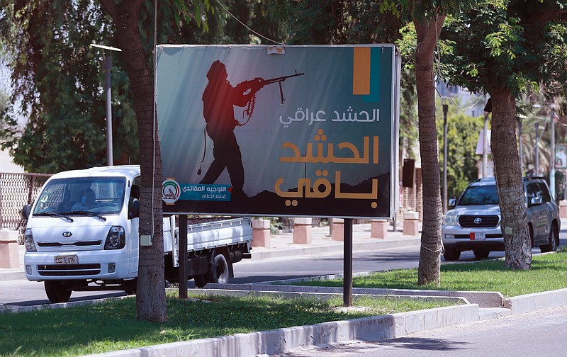 Motorists pass by a Popular Mobilization poster in Baghdad, Iraq, Friday, June 26, 2020. Iraqi security forces arrested over a dozen men suspected of a spate of rocket attacks against the U.S. (AP Photo/Hadi Mizban)