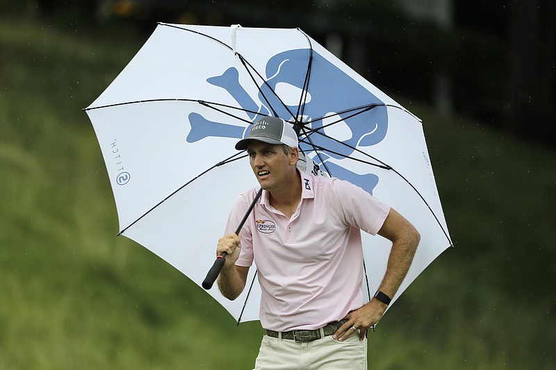 Brendon Todd looks at a competitors tee shot while sheltering from the rain with an umbrella on the 18th hole during the third round of the Travelers Championship at TPC River Highlands Saturday in Cromwell, Conn. - Photo by Frank Franklin II of The Associated Press story.lead_photo.caption