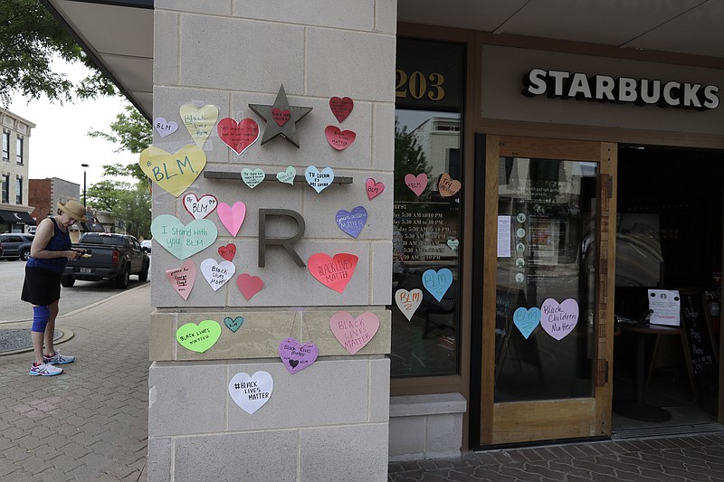Awoman looks at the plywood covering the windows of a Starbucks store on June 4 in downtown Naperville, Ill., as Naperville residents used hearts to post messages in support of the Black Lives Matter movement. Starbucks is the latest company to say it will pause social-media ads after a campaign led by civil-rights organizations called for an ad boycott of Facebook, saying it doesn't do enough to stop racist and violent content. Starbucks said Sunday that its actions were not part of the “#StopHateforProfit” campaign, but that it is pausing its social ads while talking with civil rights organizations and its media partners about how to stop hate speech online. - AP Photo/Nam Y. Huh story.lead_photo.caption