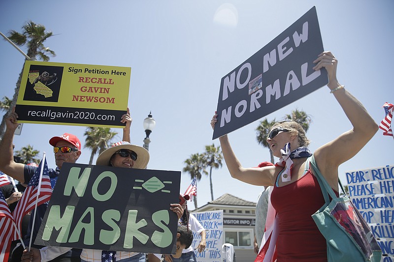 Demonstrators hold signs as they protest the lockdown and wearing masks Saturday in Huntington Beach, Calif. - AP Photo/Marcio Jose Sanchez story.lead_photo.caption