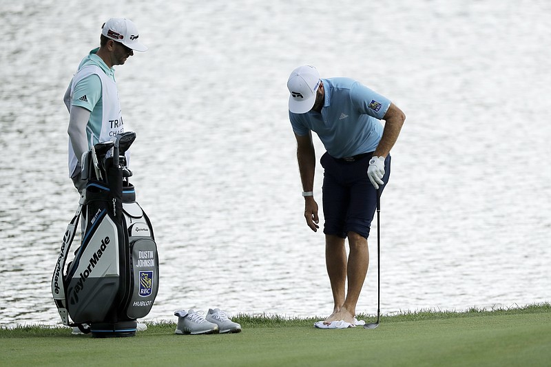 Dustin Johnson, right, cleans his feet after having to go in the pond to hit a ball on the rough on the 15th hole during the final round of the Travelers Championship at TPC River Highlands Sunday in Cromwell, Conn. Johnson's brother and caddie, Austin Johnson, looks on. - Photo by Frank Franklin II of The Associated Press story.lead_photo.caption