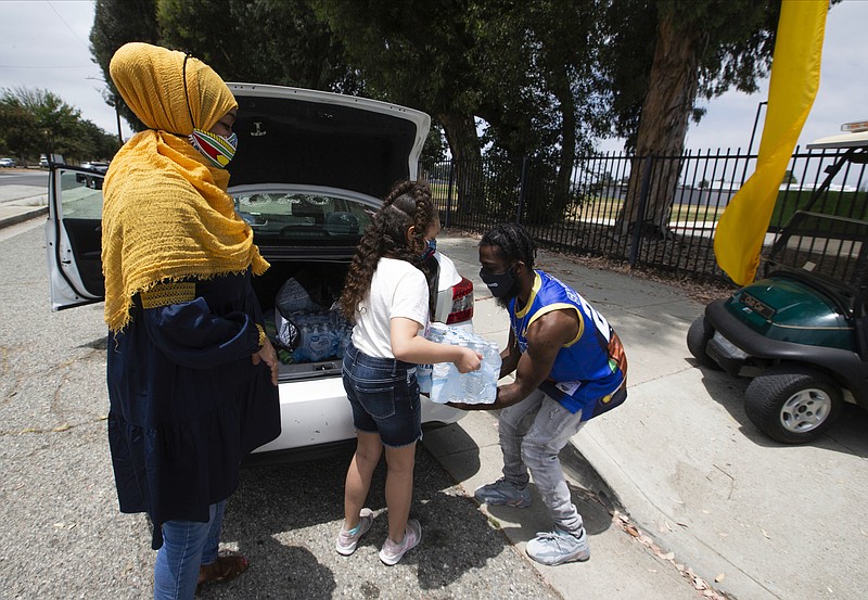 In this Friday, June 19, 2020, photo shows Margari Hill, co-founder and executive director of MuslimARC, the Muslim Anti-Racism Collaborative, who is based in San Bernardino, Calif., with her daughter, Ziyan Manley, 8, donates lunches for medical staff at a byeCOVID, a culturally-conscious initiative to honor Juneteenth and provide health services to underserved communities, being held at the Compton College in Compton, Calif. (AP Photo/Damian Dovarganes)