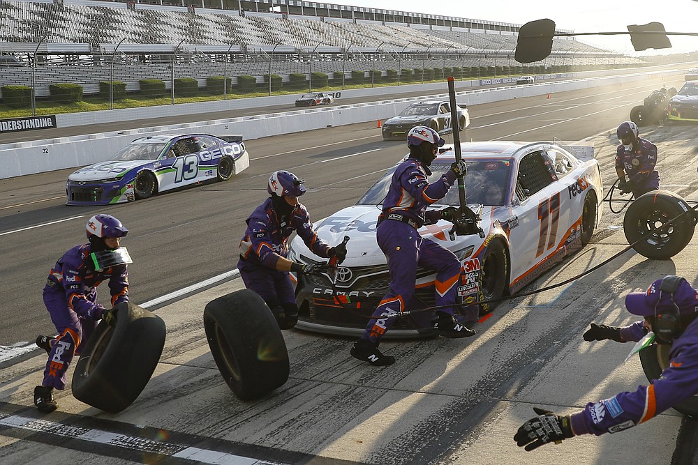 Crew members hustle to service the car of Denny Hamlin in a pit stop during a NASCAR Cup Series auto race at Pocono Raceway, Sunday, June 28, 2020, in Long Pond, Pa. (AP Photo/Matt Slocum)