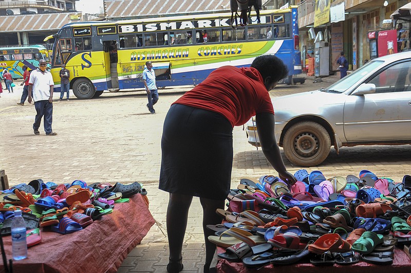 In this photo taken Saturday, June 20, 2020, Grace Twisimire, 25, adjust the display of plastic shoes for sale in her once-thriving shop in the capital Kampala, Uganda. The COVID-19 pandemic means that millions of women in Africa and other developing regions could lose years of success in contributing to household incomes, asserting their independence and expanding financial inclusion. (AP Photo/Ronald Kabuubi)