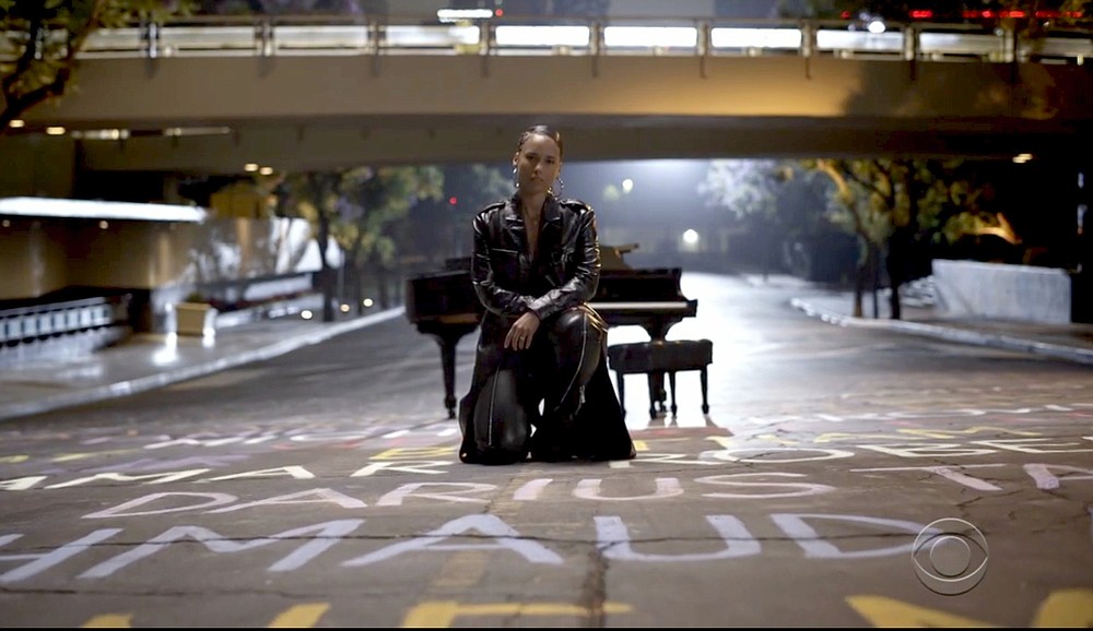 Alicia Keys, taking a knee atop names of Black lives lost, performs during show. (BET via AP)