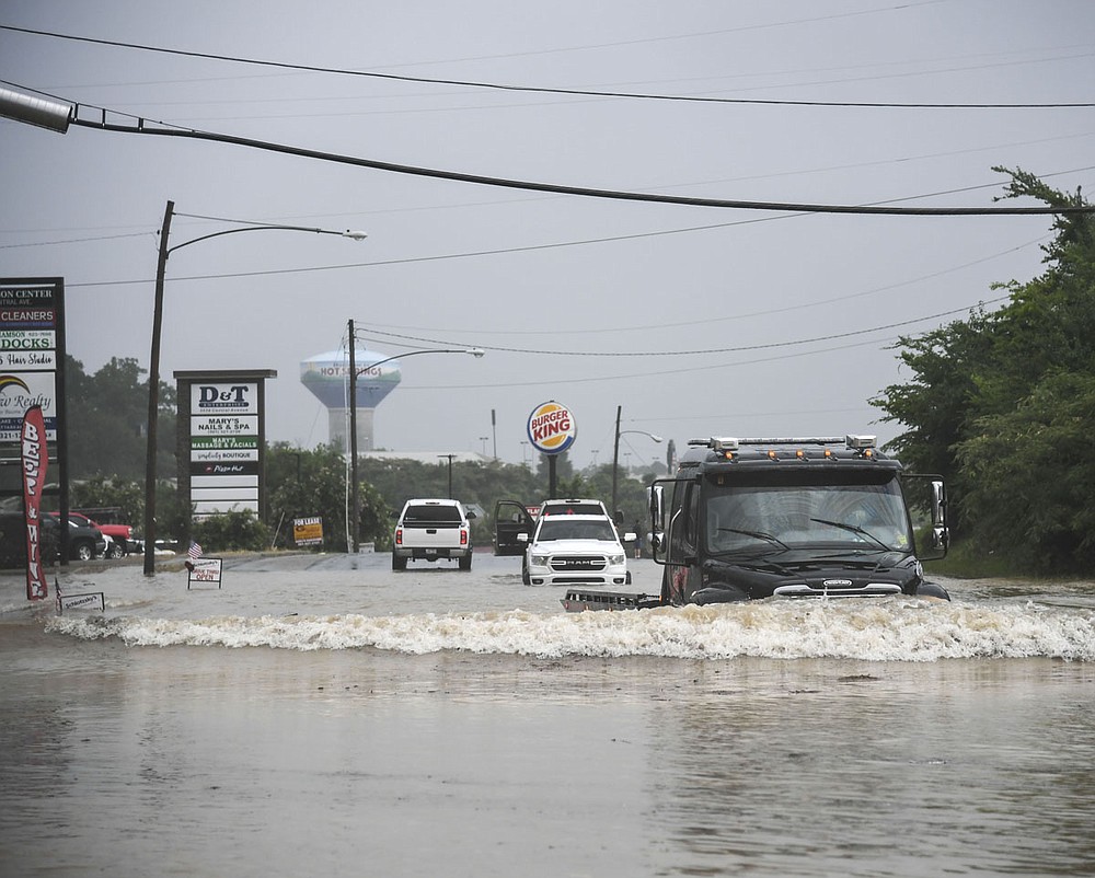 A tow truck drives through a flooded stretch of road in the 3500 block of Central Avenue Monday afternoon. - Photo by Grace Brown of The Sentinel-Record