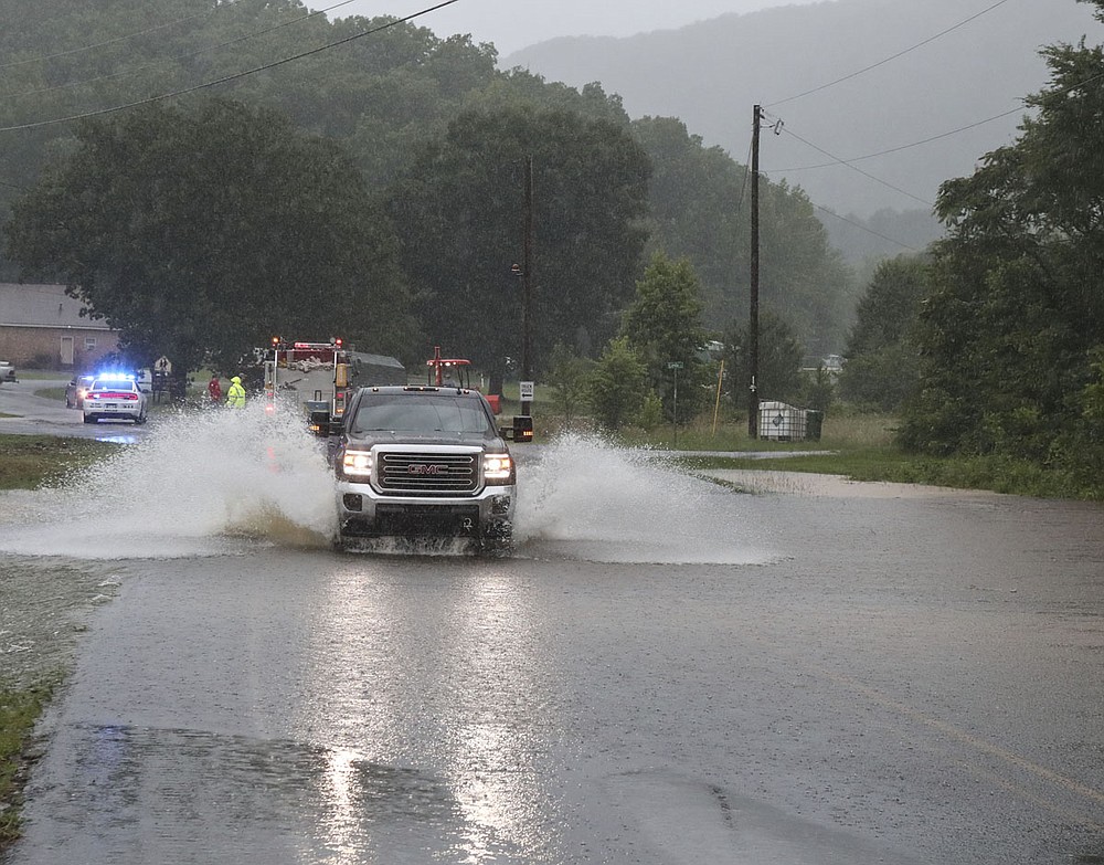 A truck leaves a flooded area of Mountain Pine near the railroad tracks and entrance to the town following heavy rains on Monday. - Photo by Richard Rasmussen of The Sentinel-Record