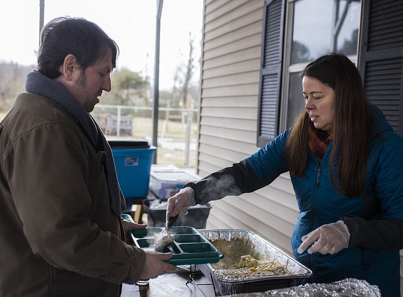 NWA Democrat-Gazette/CHARLIE KAIJO Volunteer Allison Williams serves food to volunteer James Cohen (from right) during a community food share, December 30, 2018 at the Seven Hills Day Center in Fayetteville. 

Volunteers from the group Food Not Bombs served hot meals for attendees during a community food share. They serve meals at that location on the last Sunday of every month.