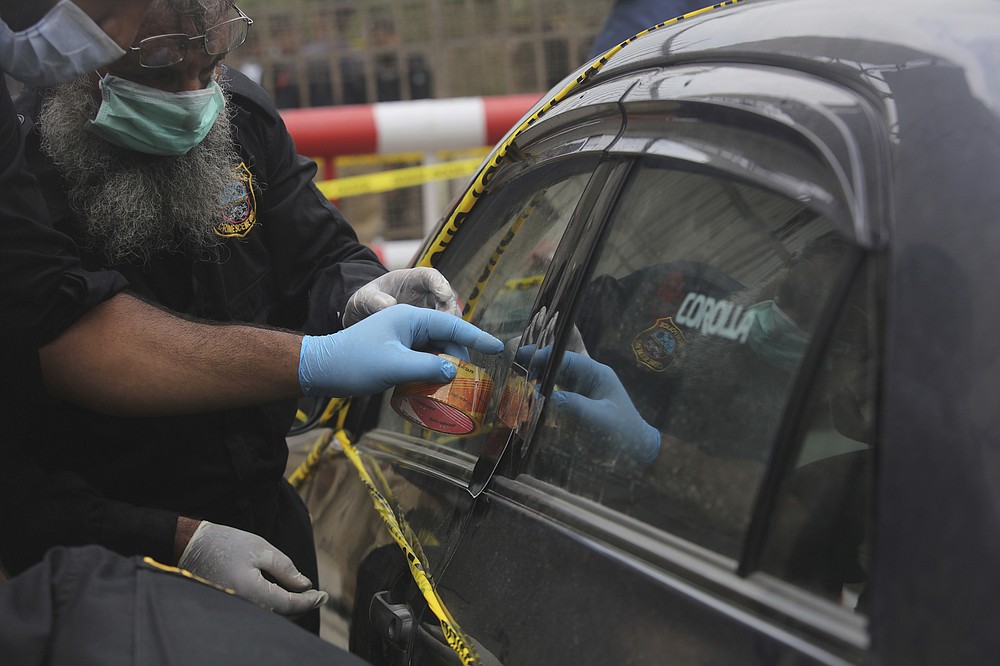 Security personnel check a car used by attackers during an attack at the Stock Exchange Building in Karachi, Pakistan, Monday, June 29, 2020. Gunmen have attacked the stock exchange in the Pakistani city of Karachi on Monday. Special police forces deployed to the scene of the attack and in a swift operation secured the building. (AP Photo/Fareed Khan)