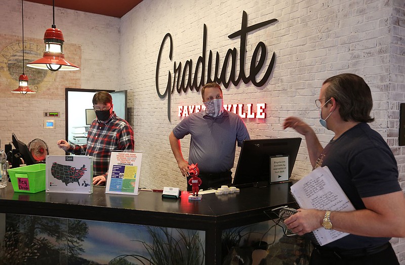 Mike VanOre (cq) (from right), with KPSQ 97.3 Fayetteville's All Volunteer Radio Station, visits with Kyle Cline, director of rooms at the Graduate Fayetteville, and John Rogers, guest services representative, Friday, June 26, 2020, in the lobby of the hotel in Fayetteville. Hotel, motel and restaurant sales tax collections fell significantly across the region in March and April when the pandemic prompted business closures across the state. Graduate Fayetteville reopened its doors to guests on Thursday. Check out nwaonline.com/200628Daily/ and nwadg.com/photos for a photo gallery.
(NWA Democrat-Gazette/David Gottschalk) story.lead_photo.caption