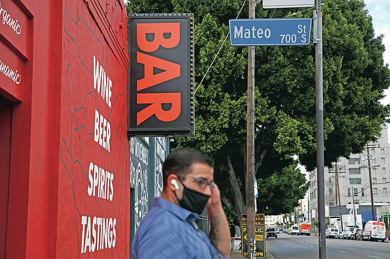 A man waits for a bus near a bar closed due to the coronavirus pandemic in Los Angeles, Monday, June 29, 2020. California Gov. Gavin Newsom on Sunday ordered bars that have opened in seven California counties, including Los Angeles, to immediately close and urged bars in eight other counties to do the same, saying the coronavirus was rapidly spreading in those parts of the state and that bar settings create a higher risk of transmission. (AP Photo/Jae C. Hong)