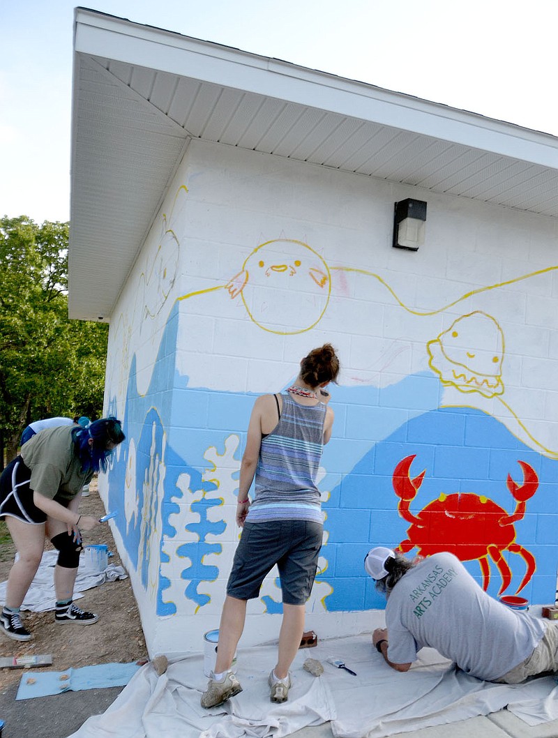 Senior art students Elizabeth Fanning and Reese Abbott paint the sea joining teacher Crystal McWilliams, center right, and teacher Aaron Jones paints a bright red crab on the mural at the Pea Ridge City Park splash pad building Thursday, July 2, 2020.
