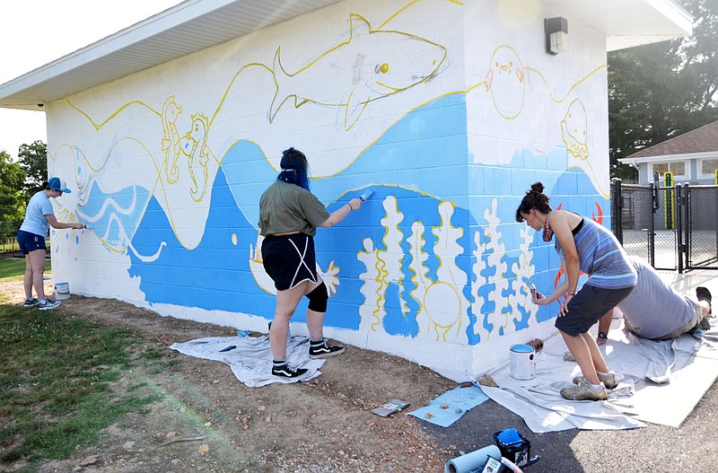 Senior art students Elizabeth Fanning, left, Reese Abbott, center, join teachers Crystal McWilliams and Aaron Jones, from the Arkansas Arts Academy, as they work on the mural on the building at the splash pad at Pea Ridge City Park.