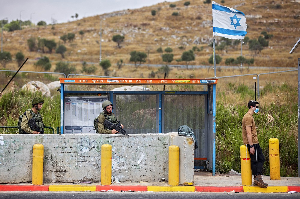 Israeli soldiers guard a bus station at the Tapuach junction next to the West Bank city of Nablus, Tuesday, June 30, 2020. Israeli Prime Minister Benjamin Netanyahu appears determined to carry out his pledge to begin annexing parts of the occupied West Bank, possibly as soon as Wednesday. (AP Photo/Oded Balilty)