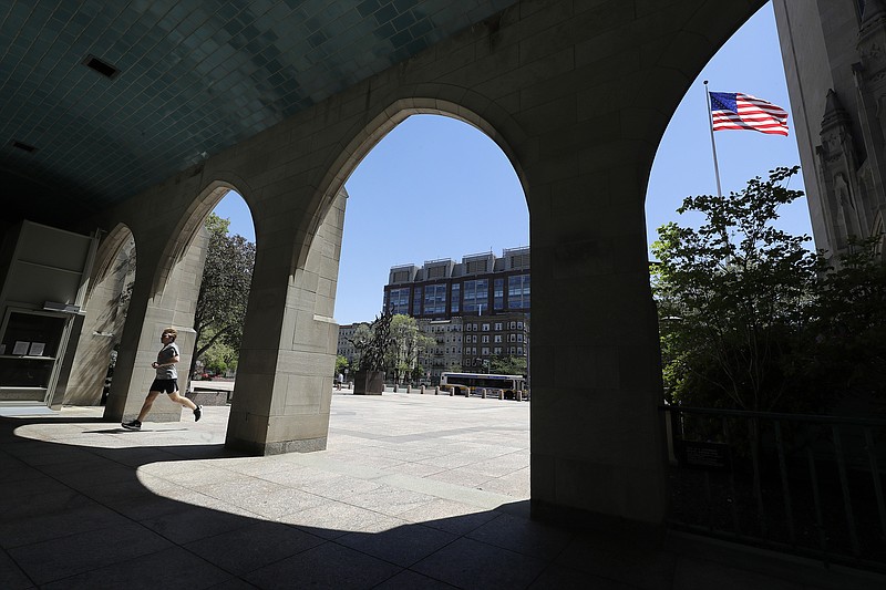 In this May 20, 2020 file photo a runner passes through an arch on the campus of Boston University, in Boston. (AP file photo/Steven Senne)