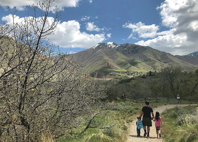 In this April 22, 2020, photo, Associated Press journalist Lindsay Whitehurst's husband, Dave Watson walks with their two children, 3, left, and 5, on a trail in suburban Salt Lake City. When the coronavirus pandemic hit, Watson suddenly became a full-time dad. Outside “adventures” became the centerpieces of their days, giving him a front-row seat to the workings of their growing minds. (AP Photo/Lindsay Whitehurst)
