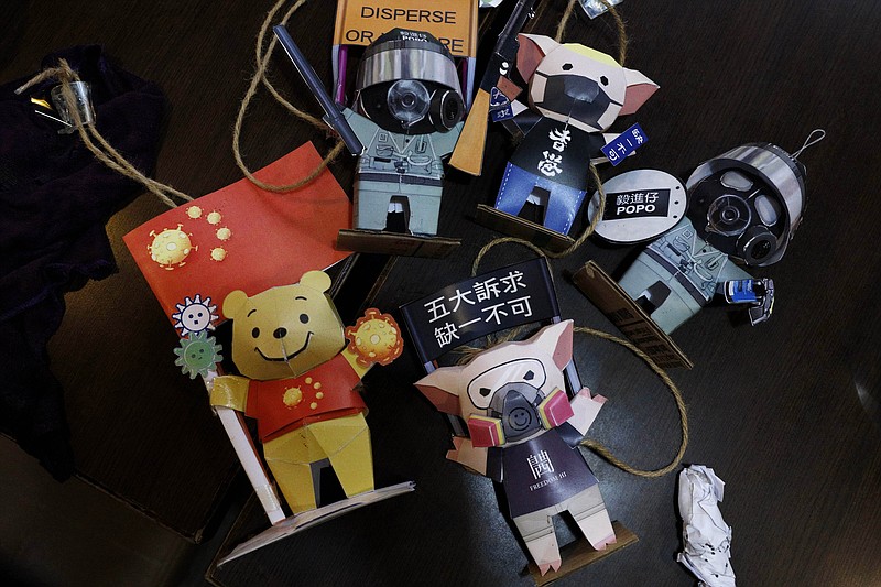 Paper figures of police officers, protesters and Winnie the Pooh, with messages in support of the pro-democracy movement are removed at a restaurant in Hong Kong, Thursday, July 2, 2020. Hong Kong police have made the first arrests under a new national security law imposed by mainland China, as thousands of people defied tear gas and pepper pellets to protest against it. Police say they arrested 10 people under the law, including at least one who was carrying a Hong Kong independence flag. (AP Photo/Kin Cheung)