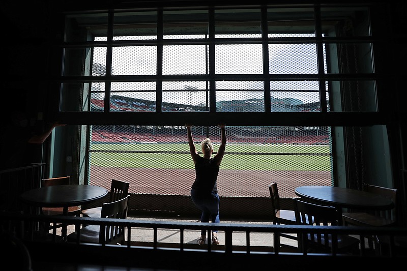 In this June 25, 2020 photo, general manager Maggie Flynn opens a large window with a view of Fenway Park from the Bleacher Bar, in Boston. Located inside the outfield structure at Fenway, it might be one of the few places where fans can watch live Major League baseball this year. (AP Photo/Elise Amendola)