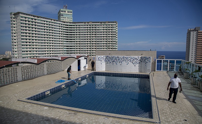 Workers do maintenance on the rooftop pool of the Capri Hotel during a lockdown affecting tourism to curb the spread of the COVID-19 pandemic in Havana, Cuba, Wednesday, June 17, 2020. Cuba's once-vibrant private hospitality sector, devastated by the three-month shutdown, remains closed to international business and will have to wait until later phases to try to begin to recover. (AP Photo/Ismael Francisco)