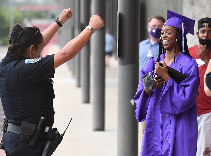 Graduate Chloe Augustine-Jefferson smiles as Fayetteville police officer Julia McKinney cheers her graduation Thursday July 2, 2020 after a social distancing ceremony at Fayetteville High School for the class of 2020. This ceremony was for FHS, Fayetteville Virtual Academy and ALLPS grads. Graduates were allowed two guests to walk with them through the school to receive their diplomas in a nearly empty auditorium. McKinney is a school resource officer at the high school. Visit nwaonline.com/200702Daily/ for photo galleries. (NWA Democrat-Gazette/J.T. Wampler)