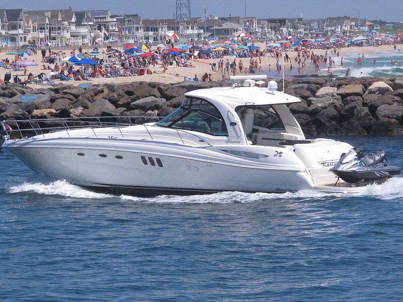 A yacht cruises through the Manasquan Inlet as a large crowd fills the beach in Manasquan, N.J. on June 28, 2020. With large crowds expected at the Jersey Shore for the July Fourth weekend, some are worried that a failure to heed mask-wearing and social distancing protocols could accelerate the spread of the coronavirus. (AP Photo/Wayne Parry)