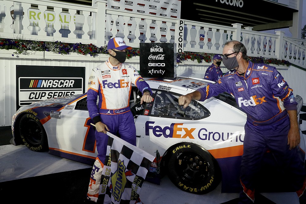 Denny Hamlin, left, celebrates with a team member after winning the NASCAR Cup Series auto race at Pocono Raceway, Sunday, June 28, 2020, in Long Pond, Pa. (AP Photo/Matt Slocum)