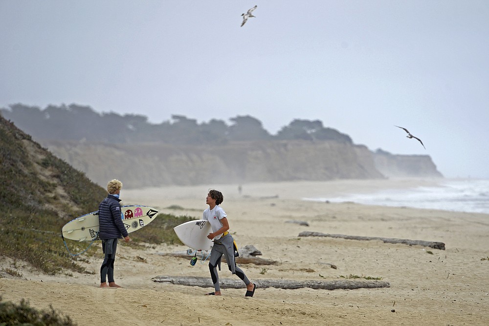 Surfers gather their belongings after being asked to leave by security patrolling the beach at Half Moon Bay State Park in Half Moon Bay, Calif., Friday, July 3, 2020. California Gov. Gavin Newsom ordered the parking lots of state beaches to close for the Fourth of July weekend to help prevent the spread of the coronavirus. Half Moon Bay added to the closure by restricting visitors access to the beach. (Jose Carlos Fajardo/Bay Area News Group via AP)