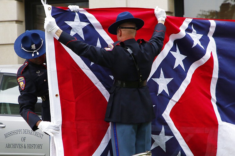 A Mississippi Highway Safety Patrol honor guard folds the retired Mississippi state flag after it was raised over the Capitol grounds one final time in Jackson, Miss., on July 1, 2020. Vestiges of the Civil War and Jim Crow segregation are coming down across the Old Confederacy as part of a national reckoning on race and white supremacy. A diversifying Democratic Party hopes the changes in symbols are part of a more fundamental shift in a region that dominated by Republicans for a generation – and white conservative Democrats a century before that. (AP Photo/Rogelio V. Solis)