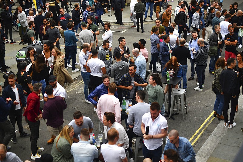 Drinkers in Soho congregate, as coronavirus lockdown restrictions eased across England, in London, Saturday July 4, 2020. England embarked on perhaps its biggest lockdown easing yet as pubs and restaurants reopened for the first time in more than three months. (Victoria Jones/PA via AP)