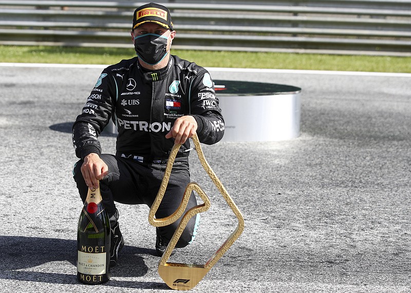 Mercedes driver Valtteri Bottas of Finland poses with his trophy and a bottle of champagne after winning the Austrian Formula One Grand Prix at the Red Bull Ring racetrack in Spielberg, Austria, Sunday, July 5, 2020. (Mark Thompson/Pool via AP)