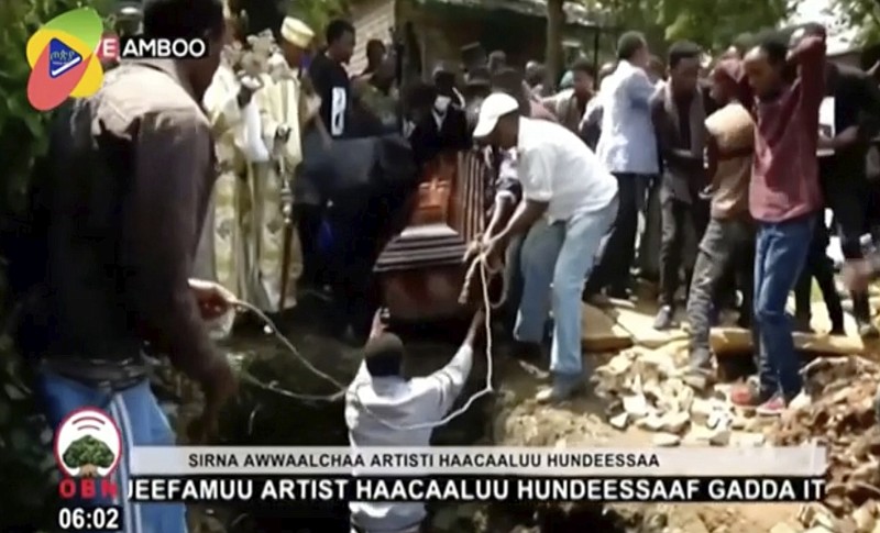 In this image taken from OBN video, the coffin carrying Ethiopia singer Hachalu Hundessa is lowered into the ground during the funeral in Ambo, Ethiopia, Thursday July 2, 2020. More than 80 people have been killed in unrest in Ethiopia after the popular singer Hachalu Hundessa was shot dead this week. He was buried Thursday amid tight security. He had been a prominent voice in anti-government protests that led to a change in leadership in 2018. (OBN via AP)