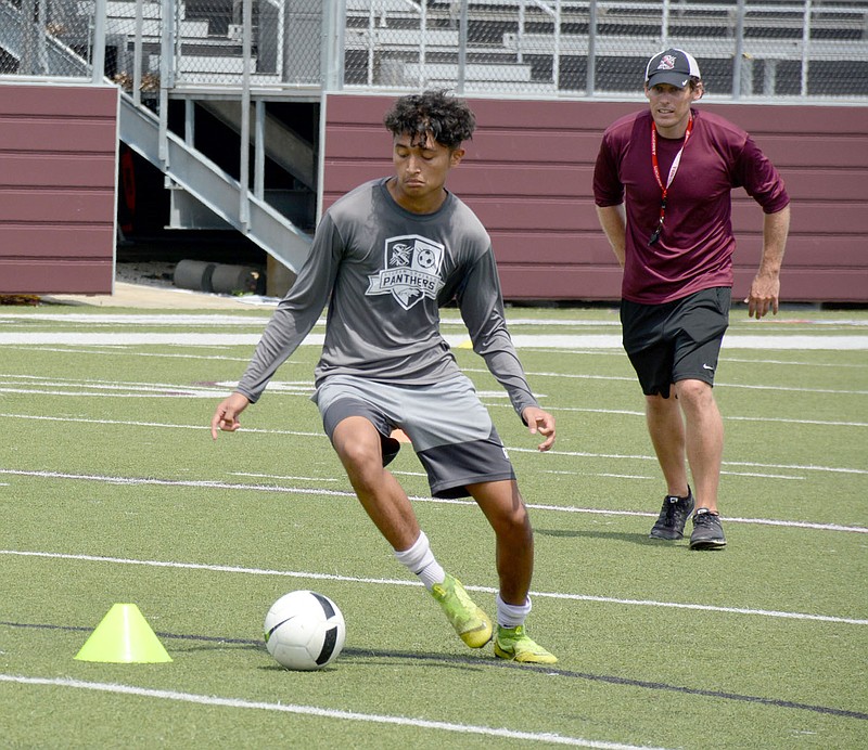 Graham Thomas/Herald-Leader
Siloam Springs boys soccer player Erik Gomez prepares to make a move as head coach Luke Shoemaker looks on during practice Monday morning at Panther Stadium.