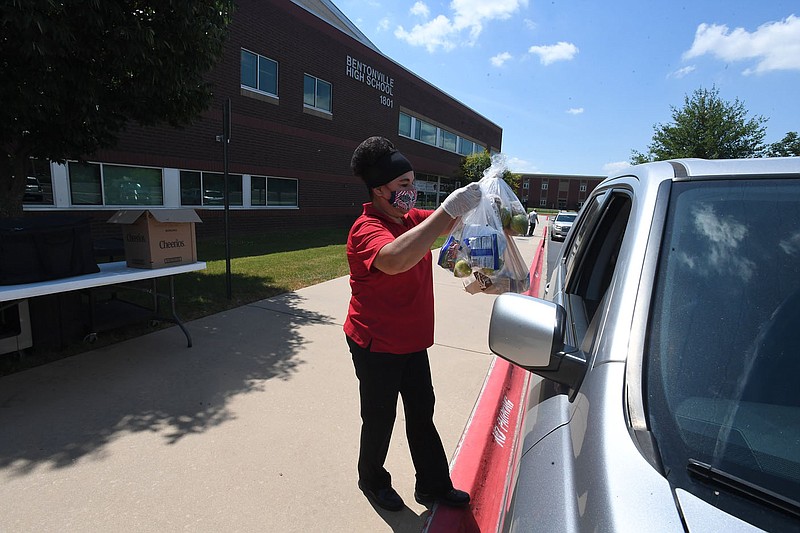 Maria Aguilar of Bentonville brings meals to waiting students Monday at Bentonville High School. The University of Arkansas for Medical Sciences (UAMS) will expand partnerships with local school districts to implement a school nutrition enrichment program in Northwest Arkansas to provide healthier food choices for students. The program expansion is supported by a $1.28 million grant from the Alice L. Walton Foundation. Visit nwaonline.com/200616Daily/ for photo galleries. 
(NWA Democrat-Gazette/J.T. Wampler)