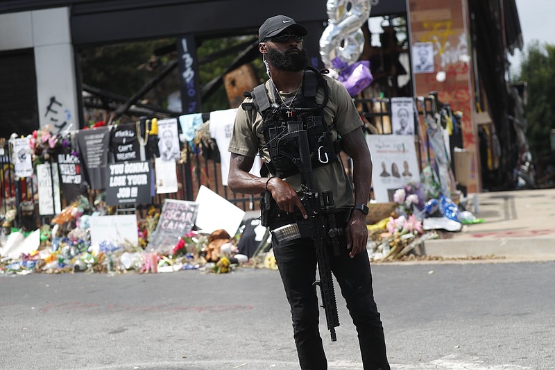 An armed protester awaits the casket of Rayshard Brooks to pass by the area where he was killed near a Wendy's restaurant on Tuesday, June 23, 2020, in Atlanta. The funeral of Brooks was held today. Brooks died after being fatally shot by an Atlanta police officer. (AP Photo/John Bazemore)