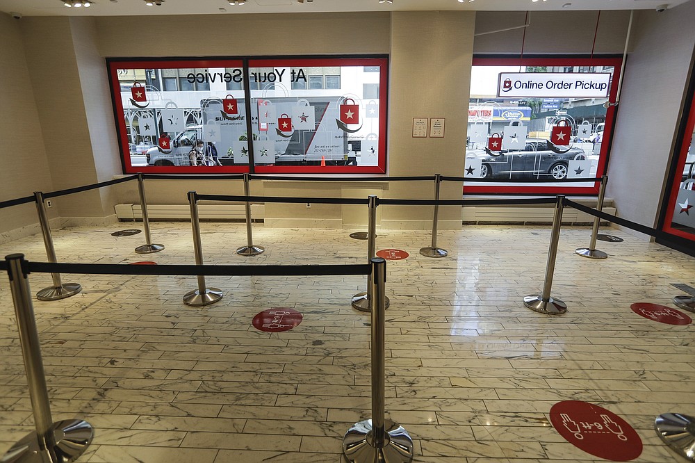 Pedestrians pass the Online Order Pickup area at the Macy's Herald Square location Friday, June 19, 2020, in New York. As Macy's and other retailers reopen their doors, shoppers face an entirely new experience. (AP Photo/Frank Franklin II)