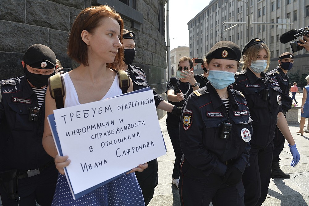 Police officers detain Yelena Chernenko, a Kommersant journalist who worked with Ivan Safronov for years, with a poster reading 'We demand justice and openness in the trial of Ivan Safonov' during a picket to protest his arrest near the building of the Federal Security Service (FSB, Soviet KGB successor) in Moscow, Russia, Tuesday, July 7, 2020. Safronov, an adviser to the director of Russia's state space corporation Roscosmos, has been detained on treason charges by the nation's top security agency. (AP Photo/Denis Kaminev)