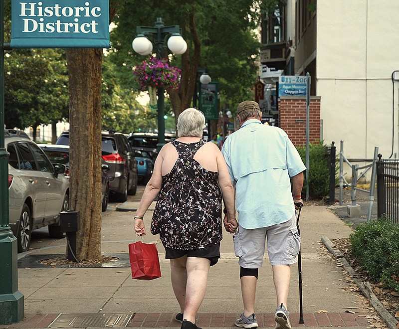 Two unidentified patrons walk hand-in-hand along downtown shops recently. - Photo by Cassidy Kendall of The Sentinel-Record