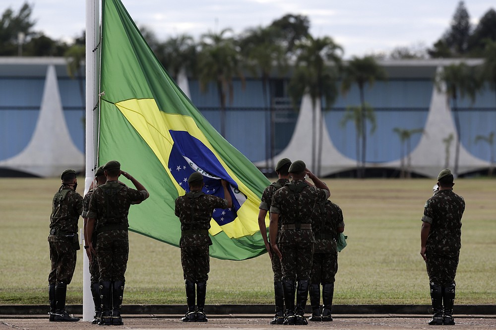 Soldiers hold the flag-raising ceremony outside the president's official residence, Alvorada Palace, in Brasilia, Brazil, Wednesday, July 8, 2020. Brazil's President Jair Bolsonaro said Tuesday he tested positive for COVID-19. (AP Photo/Eraldo Peres)